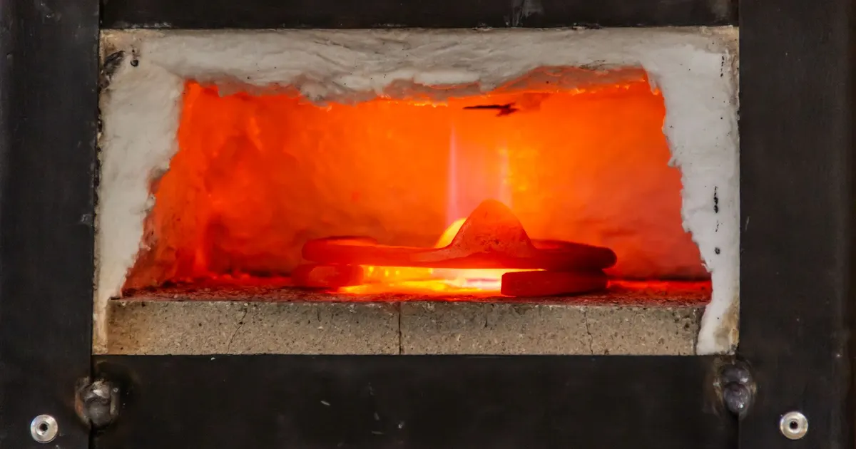 Metal piece glowing orange inside an industrial heat treat furnace