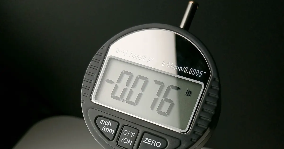 Digital indicator gauge reading minus 0.076 inch, a dimensional measurement of the kind recorded in a CMM inspection report